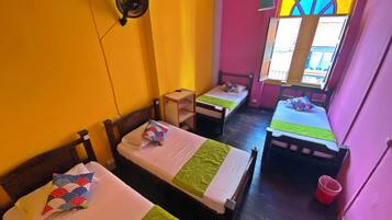 A room with two single beds, a small table, and a window with a colorful stained glass design.