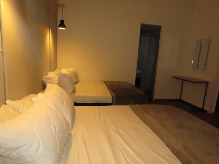 Een slaapkamer met een bed, nachtkastje en een spiegel aan de muur.