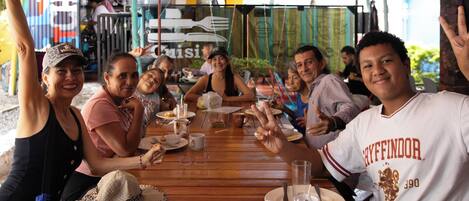 A group of people seated around a wooden table with plates, cups, and cutlery.