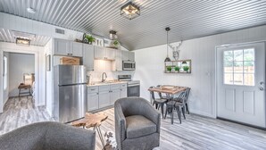 Een moderne keuken met roestvrijstalen apparatuur, een eethoek met een houten tafel, en een plafond met zichtbare balken.