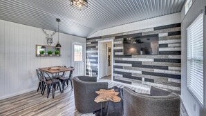 Een ruime kamer met een eethoek, een open haard en een groot raam.