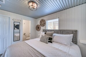 Une chambre à coucher avec un lit, un miroir, un panneau et un ventilateur de plafond.