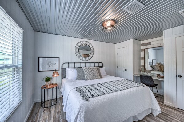 Une chambre à coucher avec un lit, une table de chevet, une lampe et un miroir.