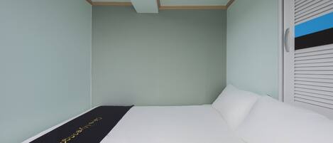 A bedroom with a bed, a black runner with gold lettering, and a window with blinds.