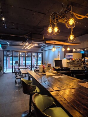A modern bar area with a wooden bar counter, bar stools, and hanging light fixtures. - Cave Myeongdong (Seoul)