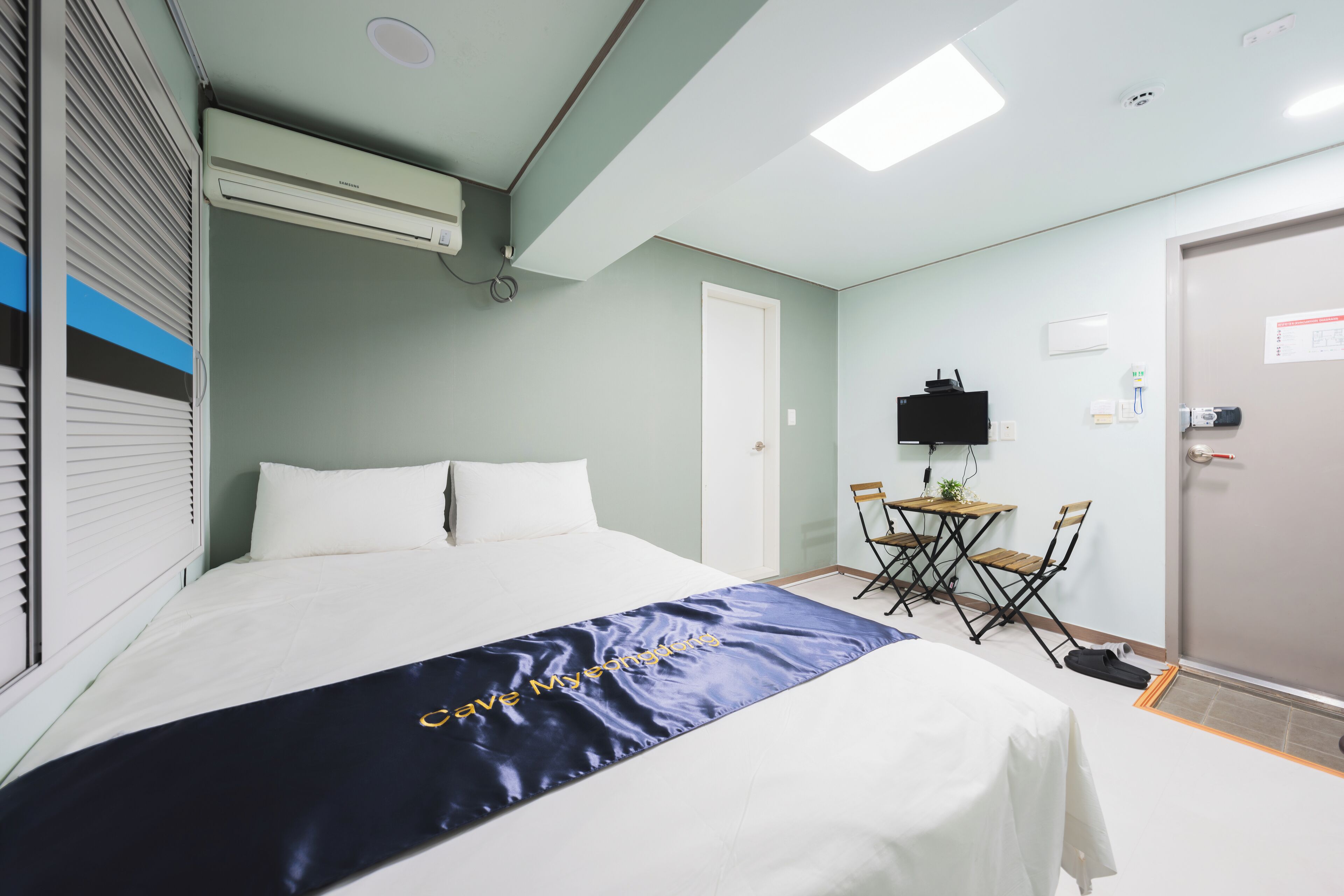 A hotel room with a bed, a desk, and a TV.