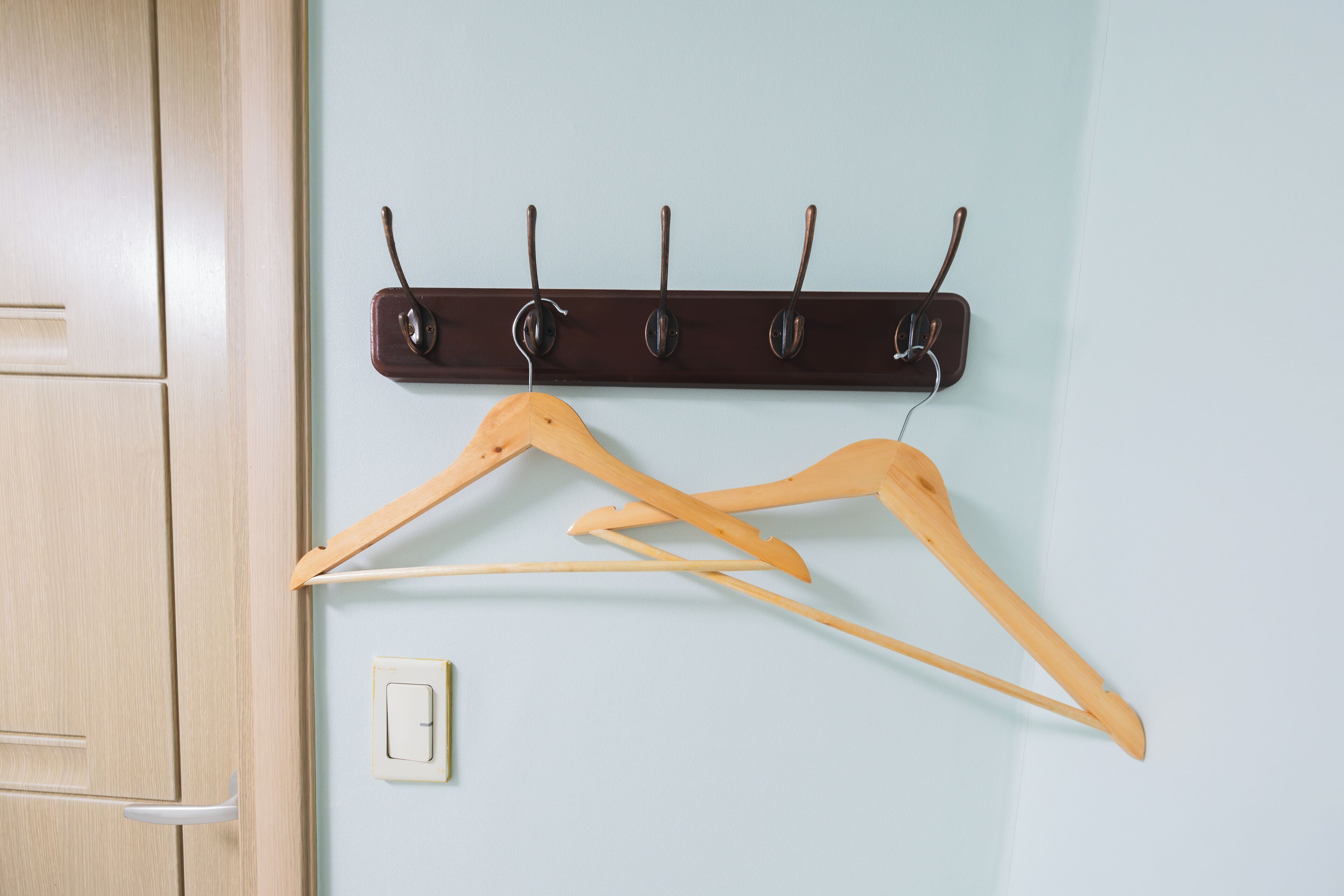 A wooden wardrobe with a light switch below it.