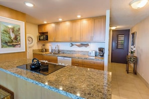 A kitchen with granite countertops, wooden cabinets, a microwave, a toaster, and a dishwasher.