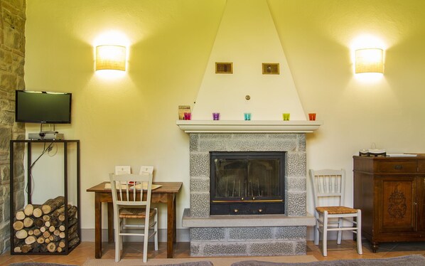 A cozy living room with a fireplace, a television, and a dining area.