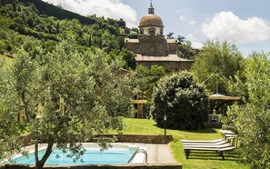 A pool area with a view of a historic building with a dome, surrounded by lush greenery.