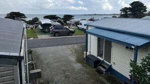 Zona residencial con una caravana, un coche y un edificio pequeño con tejado azul.