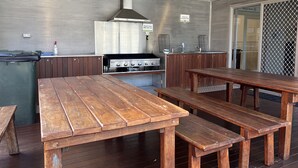Una cocina con estufa a gas, mesas y bancos de madera.