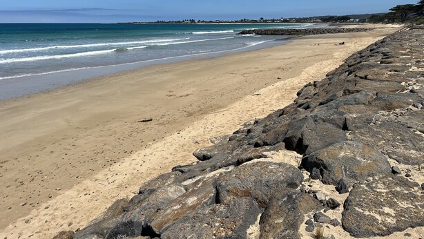 Una playa con costa rocosa y vista despejada del océano.