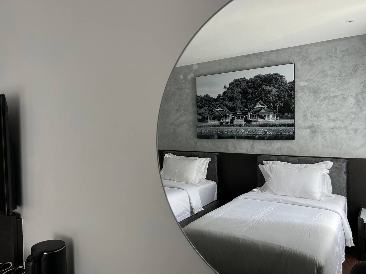 Una habitación de hotel moderna con una cama grande, dos mesitas de noche y un televisor montado en la pared.