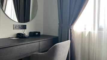 Una habitación de hotel con escritorio, una silla, teléfono y toma de corriente.