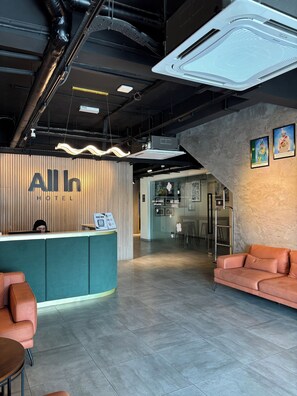 A hotel reception area with a counter, seating, and a staircase.