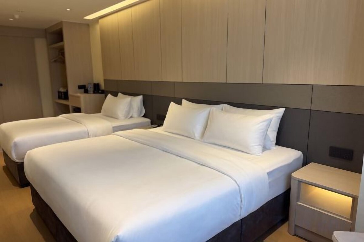 A hotel room with two beds, a bedside table, and a wardrobe.