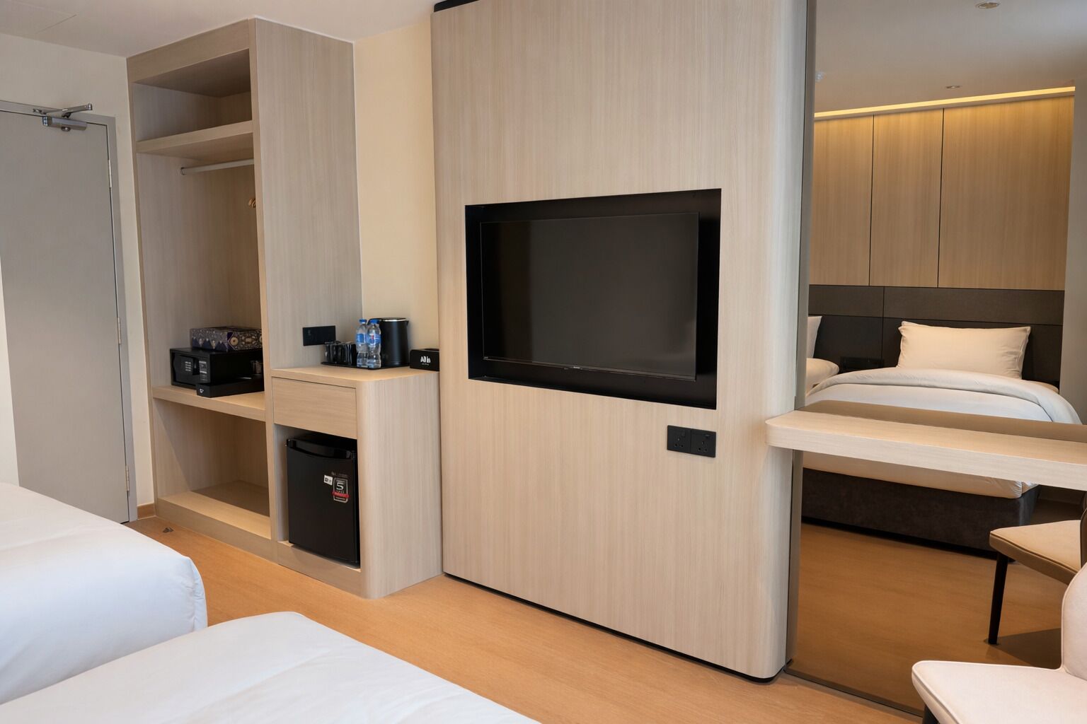 Une chambre d’hôtel moderne équipée d’un lit, d’une télévision, d’un minibar et d’un coin salon.