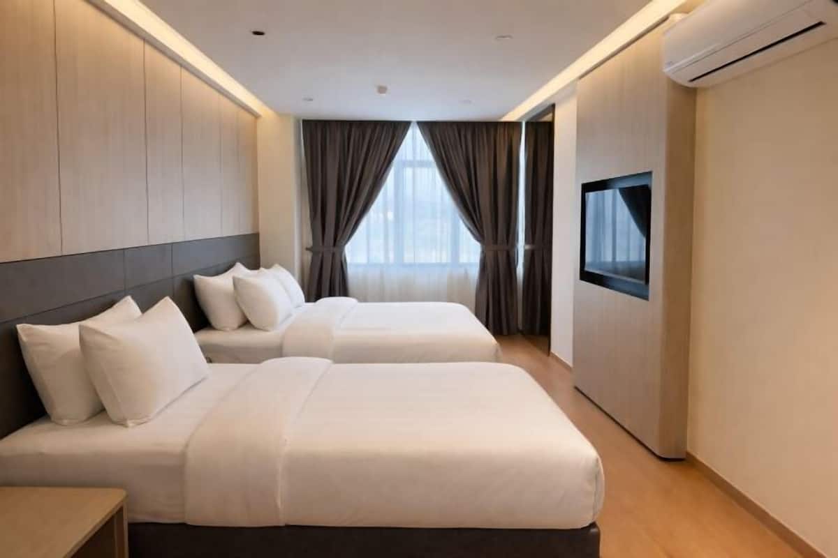 A hotel room with two beds, a TV, and an air conditioning unit.