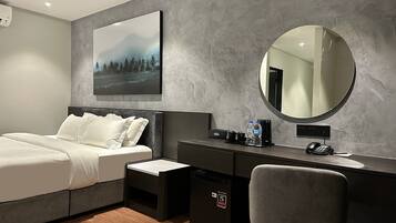 A modern bedroom with a bed, a desk, a chair, a mirror, and a painting on the wall.