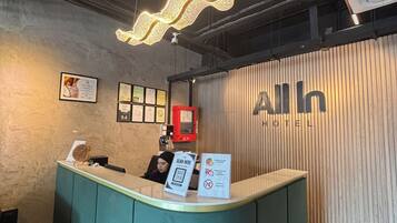 A reception desk with a digital screen, a red emergency phone, and framed certificates on the wall.