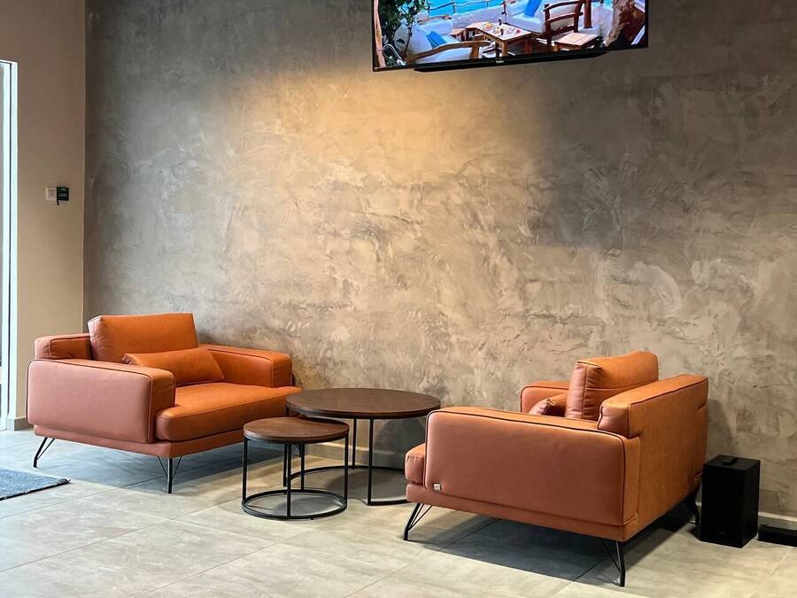 A modern living room with a sofa set, a coffee table, and a television mounted on a textured wall.