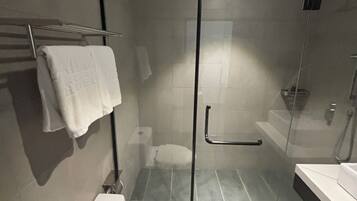 Une salle de bain moderne dotée d’une douche à parois de verre, de toilettes et d’un lavabo.