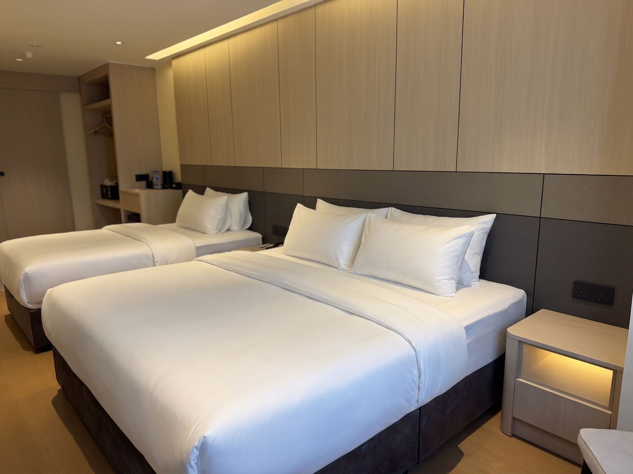 Habitación de hotel con dos camas, una mesita de noche y un armario.