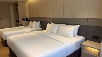 Habitación de hotel con dos camas, una mesita de noche y un armario.