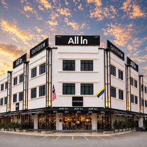 A hotel with 'All In' signage, multiple 'CAFFÉDIEM' signs, and a flag. - All In Hotel (Arau)