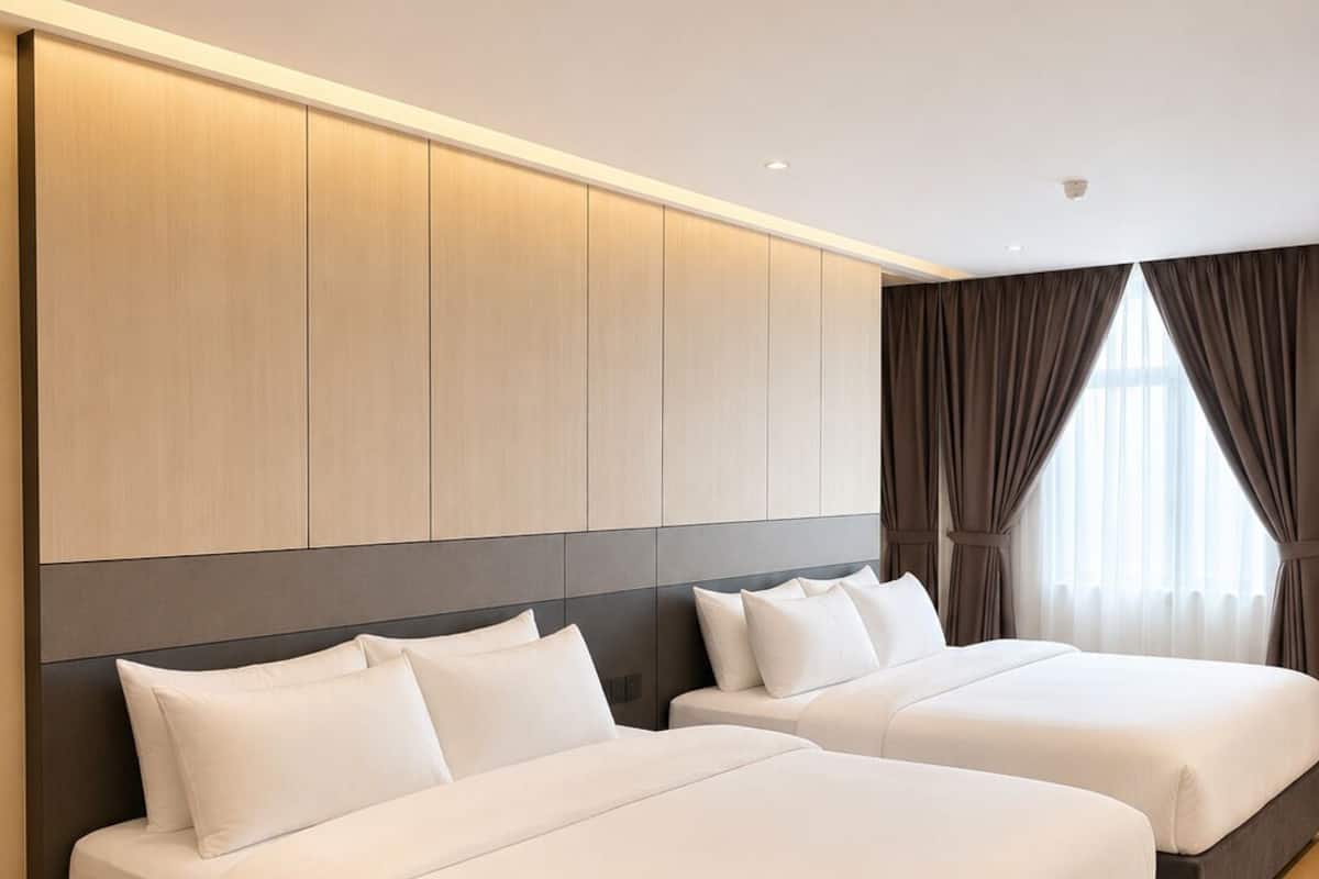 A hotel room with two beds, a large wardrobe, and a view of the outdoors.