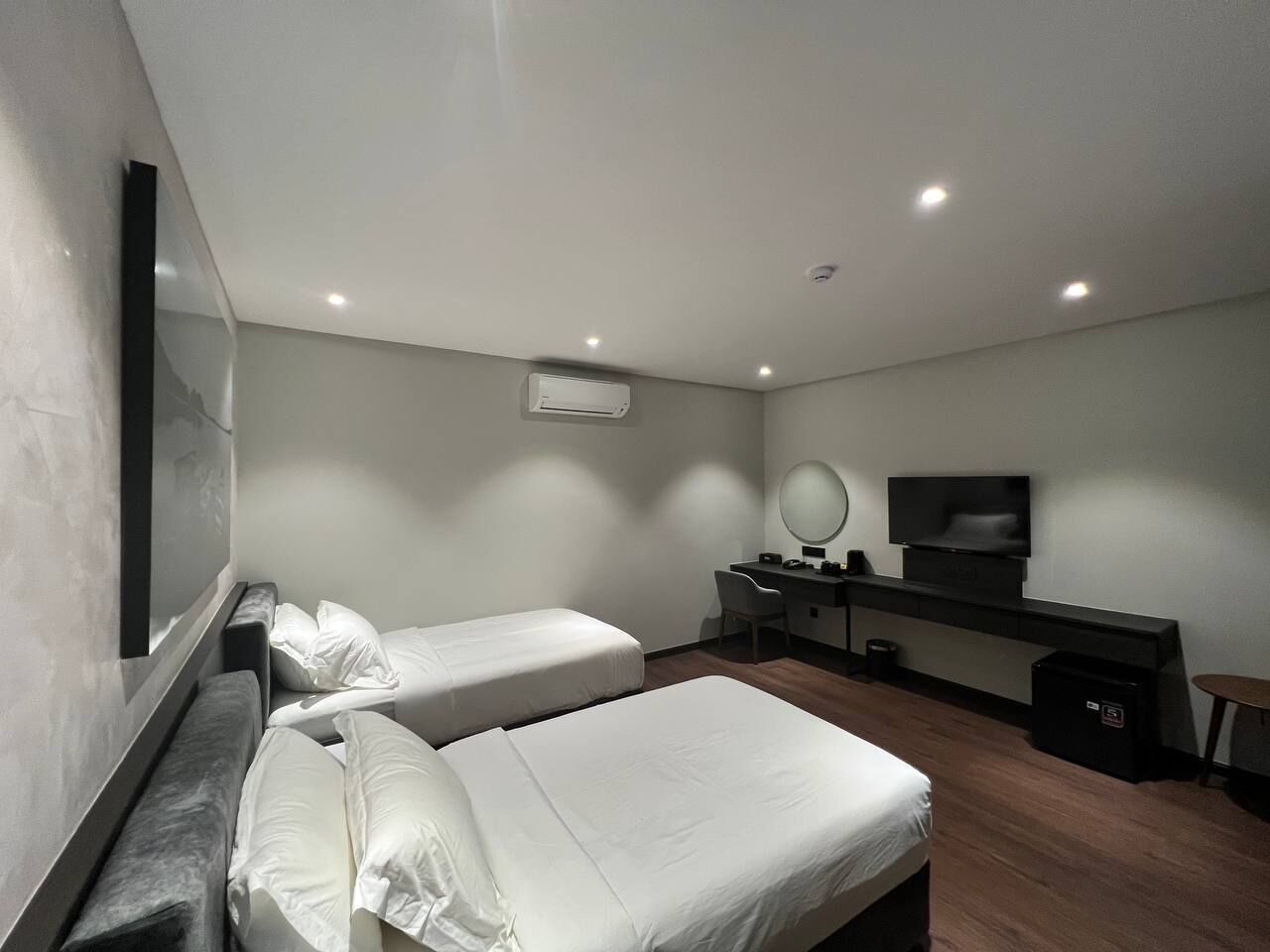 Een moderne hotelkamer met twee enkele bedden, een bureau met stoel, een flatscreen televisie en een klein tafeltje.