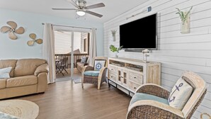 A living room with a sofa, chairs, a TV, and a ceiling fan. - Family Tides: Waves, Sun and PrimeTime fun for EvERYONE! (Carolina Beach)
