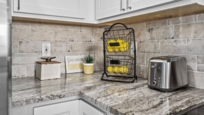 A kitchen with a granite countertop, a toaster, a yellow fruit basket, a small potted plant, and a sign with the text 'You are my sunshine.' - Family Tides: Waves, Sun and PrimeTime fun for EvERYONE! (Carolina Beach)