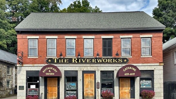 Un edificio de ladrillo con un cartel que dice 'The Riverworks' y 'Catering' con un número de teléfono.