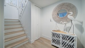 A staircase with wooden steps and white walls, a white door, and a decorative console table with a woven mirror and a white swan sculpture. - Welcome to your Dream Villa in the Florida Keys! (Key Largo)
