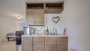 A compact kitchen with wooden cabinets, a built-in wine rack, a coffee machine, and a sink. - Welcome to your Dream Villa in the Florida Keys! (Key Largo)