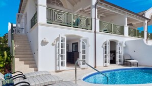 Un edificio de dos pisos con piscina, asientos al aire libre y una escalera que lleva al nivel superior.