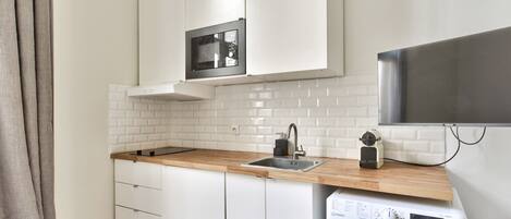 A compact kitchen with a built-in microwave, a sink, and a washing machine.