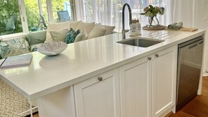 Una cocina moderna con encimera blanca, pileta de acero inoxidable y lavavajillas integrado.