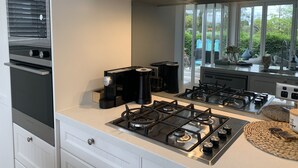 Una cocina moderna con electrodomésticos de acero inoxidable, estufa a gas y un amplio ventanal con vistas al exterior.