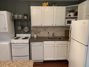 A kitchen with white cabinets, a stove, a dishwasher, and a refrigerator.