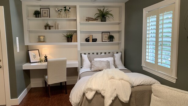 Ein Schlafzimmer mit Bett, Schreibtisch und Regale.