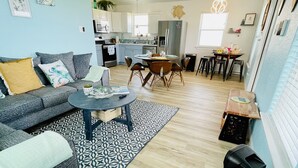 A modern living room with a grey sofa, a coffee table, and decorative bowls. A dining area with a wooden table and chairs is visible in the background. - Homelike beach house  (Freeport)