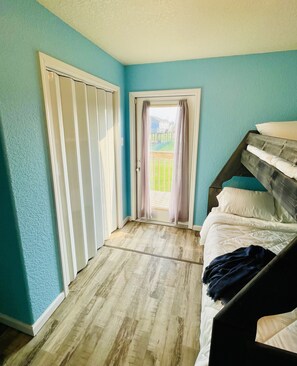 Une chambre avec un lit superposé, une porte coulissante et une vue sur le jardin.
