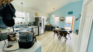 A kitchen with a refrigerator, sink, and a dining area with chairs and a table. - Homelike beach house  (Freeport)