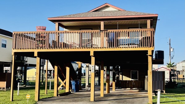 Une construction en bois à deux étages, dotée d’un balcon, d’un espace couvert et d’une cour clôturée.