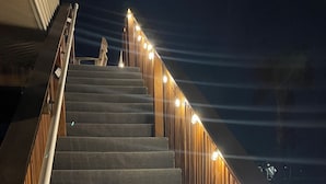 A staircase with wooden railings and lights along the handrails. - Homelike beach house  (Freeport)