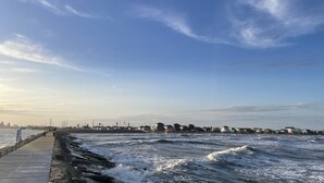 A coastal walkway with a view of the sea and distant buildings. - Homelike beach house  (Freeport)