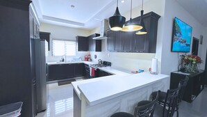 A modern kitchen with dark cabinets, a white countertop, and pendant lighting. - Pyramid Bliss - One Bedroom (Ocho Rios)